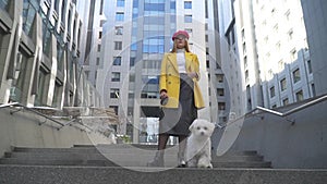 Young girl with the dog is standing in the foreground of building