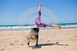 Young girl doing cartwheel at beach