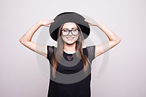 Young girl doing emotion. Dressed in a black shirt, black hat, glasses.