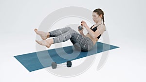 Young girl doing exercises with dumbbells and twisting for the press. The girl practices yoga on a gymnastic mat.