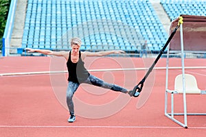 Young girl doing exercises outdoors using slings