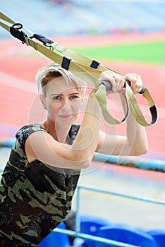 Young girl doing exercises outdoors using slings, TRX loop
