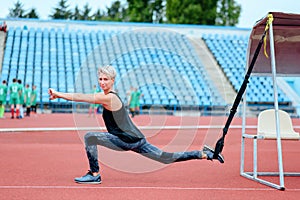 Young girl doing exercises outdoors using TRX loop. Bulgarian lunge.