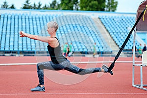 Young girl doing exercises outdoors using TRX loop. Bulgarian lunge.