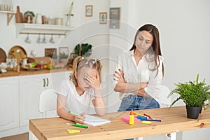 Young girl doing homework during extra-curricular classes with a tutor. Frustrated young mother or tutor teaching kid at