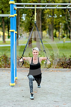 Young girl doing lunge to the side in the park. Uses TRX