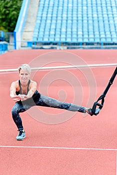 young girl doing lunge to the side TRX loop on the stadium