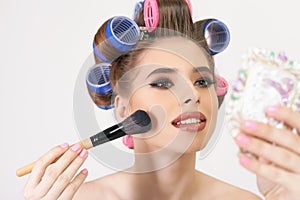 Young girl doing makeup and hairstyle using curlers