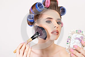 Young girl doing makeup and hairstyle using curlers