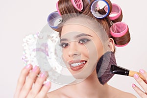 Young girl doing makeup and hairstyle using curlers