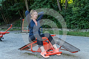 Young girl doing sports on outdoor exercise machine in the stadium