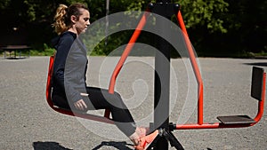 Young girl doing sports on outdoor simulators in the stadium