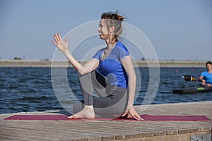 Young girl doing yoga or fitness exercise outdoor in nature with beautiful lake. Meditation and Relax concept