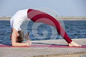 Young girl doing yoga or fitness exercise outdoor in nature with beautiful lake. Meditation and Relax concept