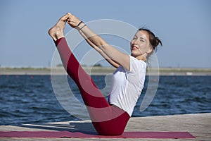 Young girl doing yoga or fitness exercise outdoor in nature with beautiful lake. Meditation and Relax concept