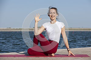 Young girl doing yoga or fitness exercise outdoor in nature with beautiful lake. Meditation and Relax concept