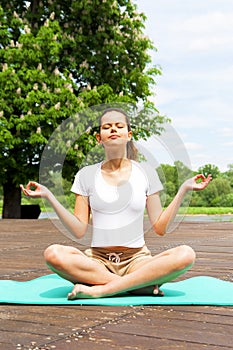 Young girl doing yoga in the park. lotos position.
