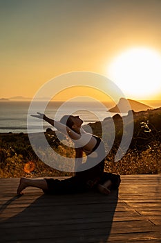 Young girl doing yoga at sunset and sea landscape.