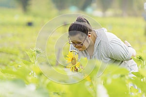 Young girl with down syndrome exploring sunflower with magnifying glass