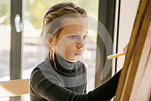 Young girl drawing on a canvas with easel