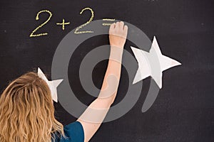 Young girl drawing question mark on a black background. woman drawing question mark for the math task on the board