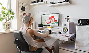 A young girl draws on a PC using a graphics tablet in her comfortable home office.