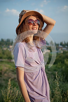 Young girl in dress is having great time during vacation in the summer on sky background in nature, travelling concept