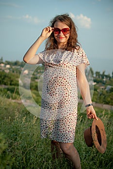 Young girl in dress is having great time during vacation in the summer on sky background in nature, travelling concept