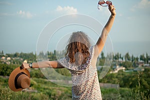 Young girl in dress is having great time during vacation in the summer on sky background in nature, travelling concept