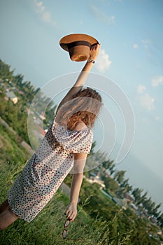 Young girl in dress is having great time during vacation in the summer on sky background in nature, travelling concept