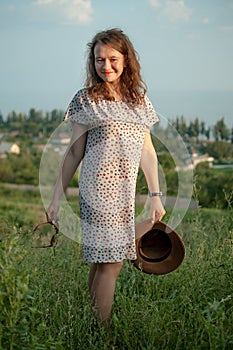 Young girl in dress is having great time during vacation in the summer on sky background in nature, travelling concept