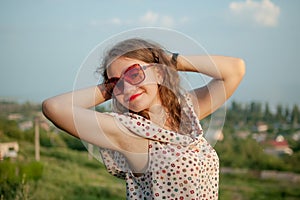 Young girl in dress is having great time during vacation in the summer on sky background in nature, travelling concept