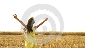 Young girl in the dress is running across the field.