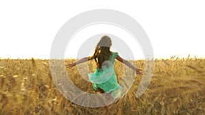 Young girl in the dress is running across the field.