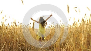 Young girl in the dress is running across the field.