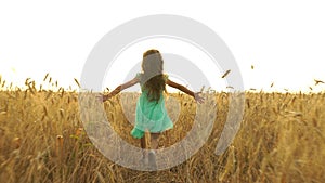 Young girl in the dress is running across the field.