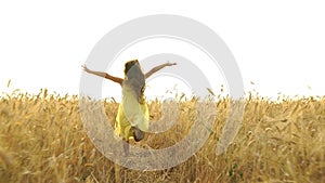 Young girl in the dress is running across the field.