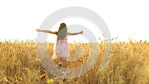 Young girl in the dress is running across the field.