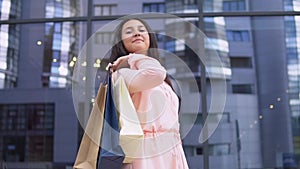 Young girl in a dress after shopping with packages in hands is happy with purchases. slow motion.