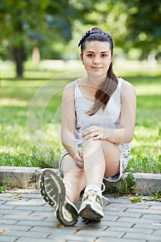 Young girl dressed in sports way sits on curb of