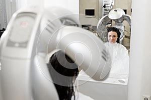 Young girl dries her hair in a hairdresser with a professional hair dryer. Portrait of a young woman in a Barber shop.