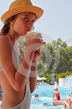 Young girl with drink at poolside