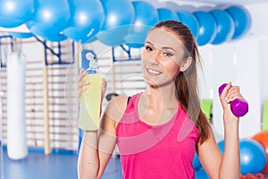 Young girl drinking isotonic drink, gym. She is happy and full o