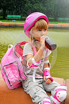 Young girl drinking and rollerskating