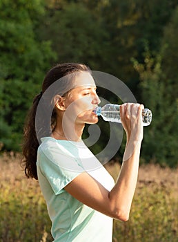 Young girl drinking water outdoors. Sport and fitness