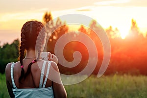 A young girl drinks coffee and looks into the distance to the sunset, waiting for someone. The concept of expectation, longing,