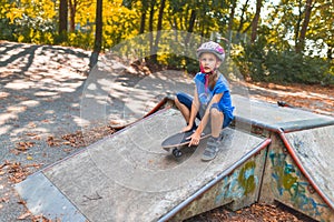 A young girl is driving down a ranp sitting on the longboard