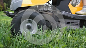 Young girl driving lawn mover cutting green grass in garden. Gardener service concept.