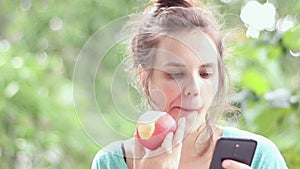 Young girl eating an apple and use on the phone