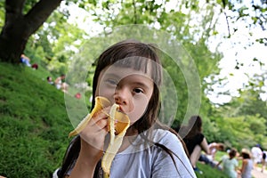 Young girl eating banana in the park